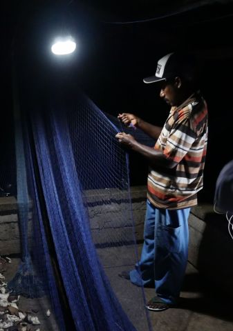捐赠的太阳能灯助力夜间修补渔网，从而提高渔业生产力。（照片：美国商业资讯）