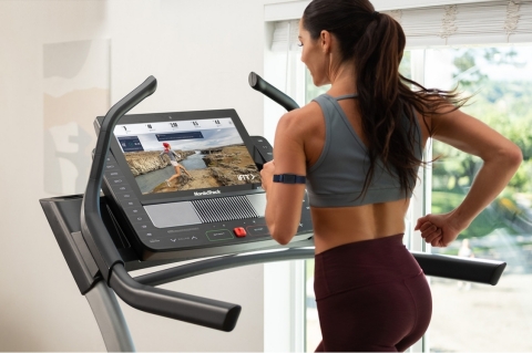 An iFit user wears the iFit SmartBeat forearm heart rate monitor, while ActivePulse technology automatically adjusts the treadmill’s speed and incline to keep her in the optimal heart rate zone. (Photo: Business Wire)