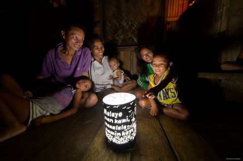 一家人坐在以手工製燈罩裝飾的太陽能燈四周（照片：美國商業資訊） 