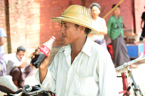 一位緬甸市民正在飲一瓶60多年來首次在該國生產的可口可樂（照片：美國商業資訊） 